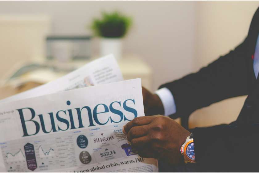 black person in suit holding a business newspaper