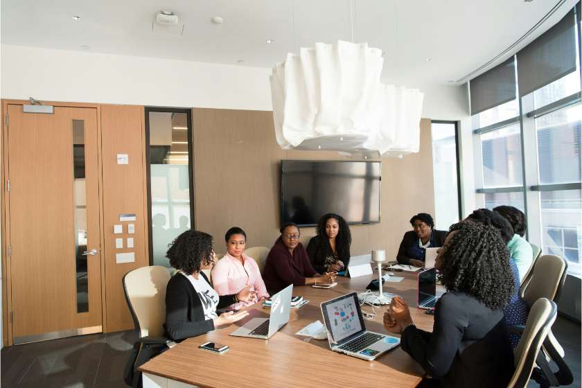 group of black people on a table in a meeting with laptops in their front
