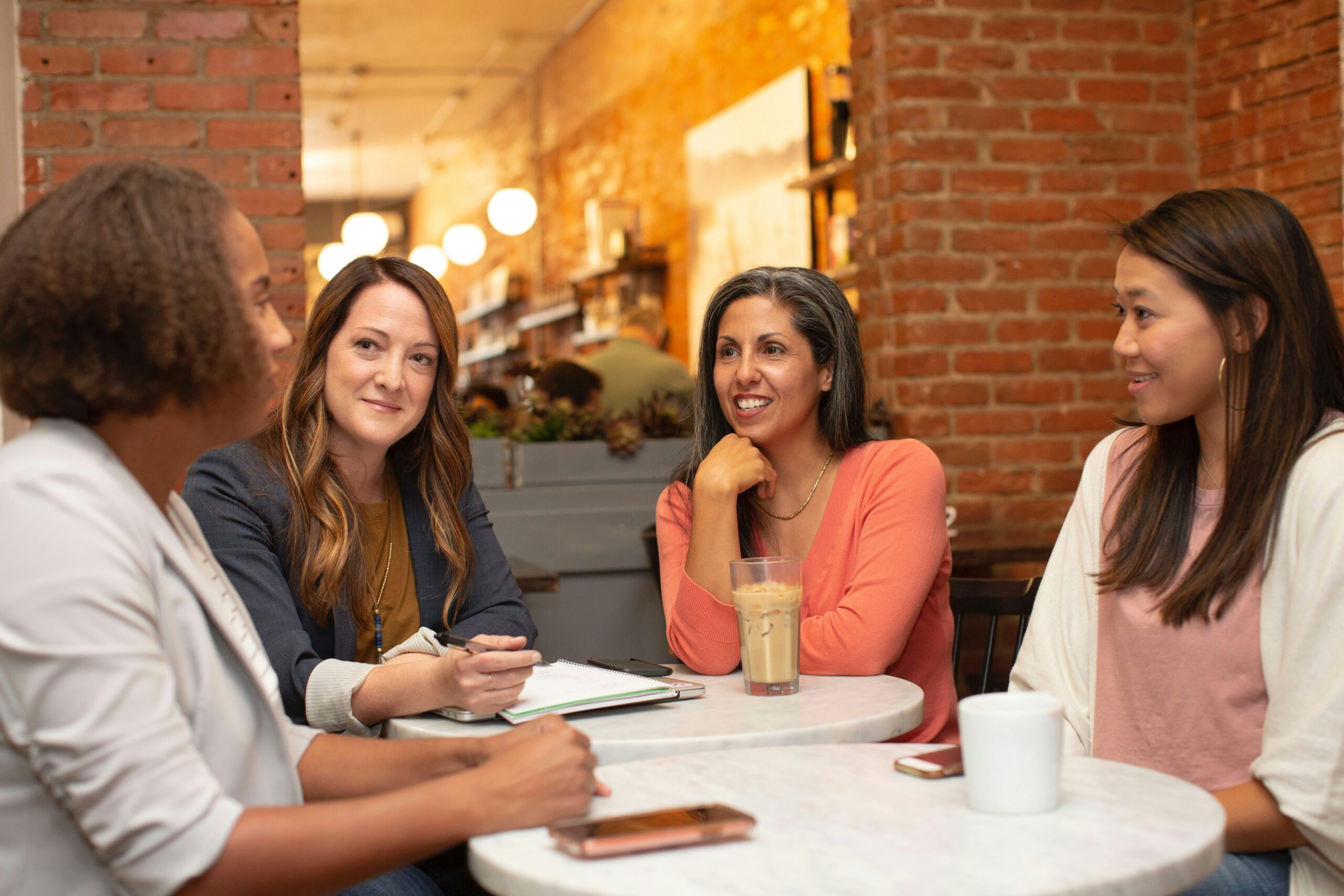 four women on a meeting with coffee and notebook on a table